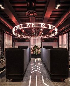 the inside of a building with black couches and neon signs on it's ceiling