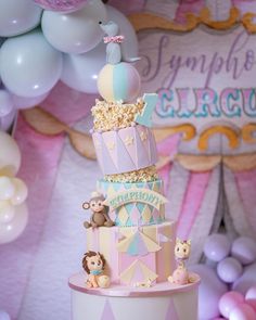 a three tiered cake decorated with animals and balloons