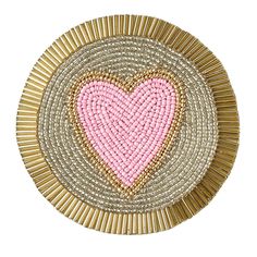 a pink heart on a gold and white plate with beadwork in the center