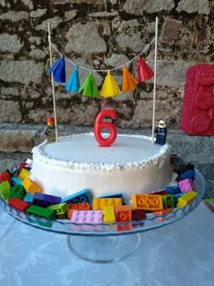 a birthday cake decorated with legos and bunting on a table in front of a stone wall