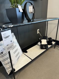 a glass shelf with some black and white items sitting on it's sides next to a potted plant