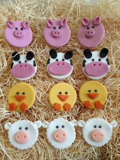 decorated cookies in the shape of farm animals and pigs on some hay with straw behind them