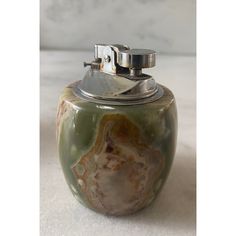 a green and white jar with a silver lid