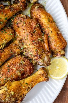 chicken wings with lemon wedges and herbs on a white plate, ready to be eaten