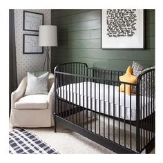 a baby's room with a chair, crib and pictures on the wall