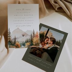 two wedding cards with an image of a couple kissing on the forehead and mountains in the background