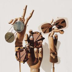 two wooden hand sculptures with sunglasses on them and one holding up the other's hands