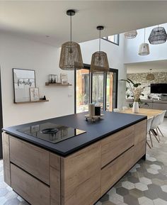 a large kitchen with an island in the middle and two pendant lights hanging from the ceiling