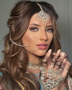 a woman with long brown hair and jewelry on her face, wearing an elaborate head piece