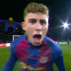 a young man making a face while standing on a soccer field at night with his mouth wide open