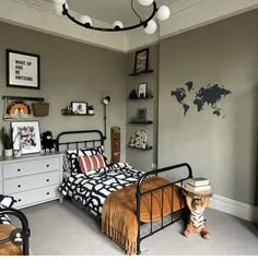 a bed room with a neatly made bed next to a dresser and a map on the wall