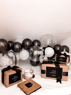 black and white balloons are on display in front of boxes with cake, napkins, and other items