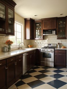 a kitchen with black and white checkered flooring, brown cabinets and stainless steel appliances