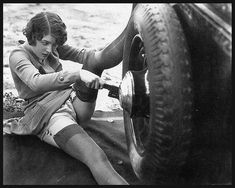 a woman sitting on the ground next to a tire