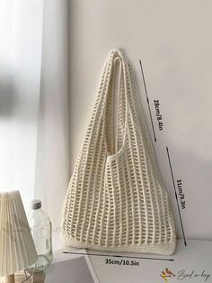 a white crochet bag sitting on top of a table next to a lamp