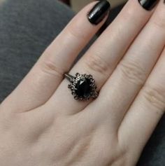 a woman's hand with black nail polish and a ring on her left hand