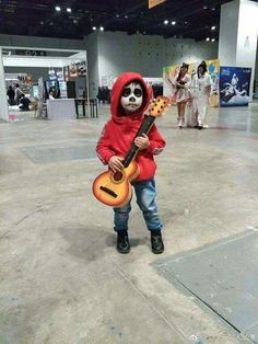 a kid in a red hoodie is holding a guitar and wearing a skeleton mask