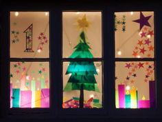 a christmas tree made out of paper sitting in front of a window with lit candles