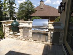 an outdoor kitchen with grill, sink and garbage can