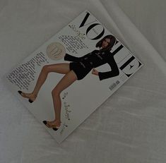 a magazine with an image of a woman in high heels on the front cover is laying on a white sheet