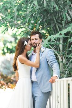 a bride and groom standing next to each other in front of a white picket fence