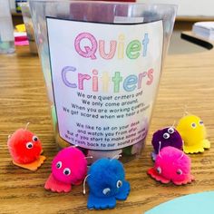 there are some little stuffed animals sitting on the table next to a sign that says quiet critters