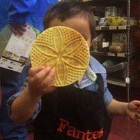 a young boy holding up a yellow frisbee in front of his face at a store