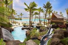 a water slide in the middle of a tropical resort with palm trees and blue waters