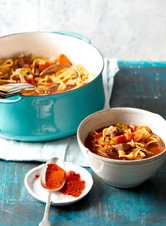 two bowls of soup on a table with spoons