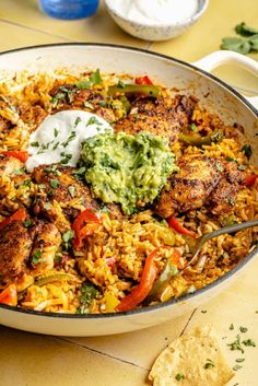 a pan filled with rice and meat covered in guacamole