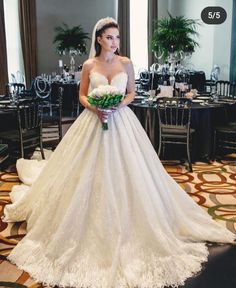 a woman in a white wedding dress standing next to a table with flowers on it