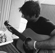 a man is playing an acoustic guitar on the table with food in front of him