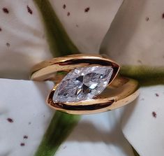 a close up of a ring with a diamond in it on top of a flower