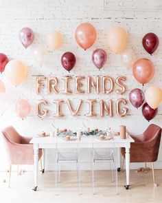 balloons are hanging on the wall above a dining room table with two chairs and a sign that says friends giving