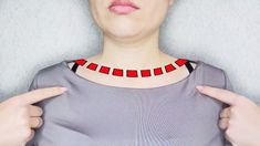 a woman wearing a red and black necklace with two hands on her chest, making the middle finger sign