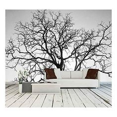 a white couch sitting in front of a black and white tree wall decal on a wooden floor