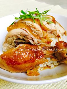 a white plate topped with meat and rice covered in sauce on top of a table