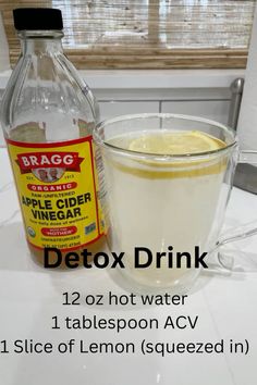 a bottle of apple cider vinegar next to a cup of water