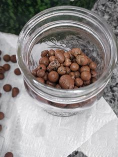 a glass jar filled with lots of food on top of a white napkin next to some chocolate chips