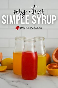 three jars filled with oranges and grapefruit on top of a marble counter