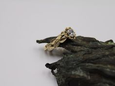 a gold ring sitting on top of a piece of driftwood with a diamond in the center