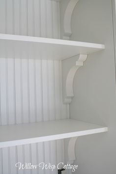 two white shelves in the corner of a room