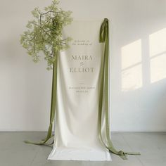 a white chair with a green ribbon tied around it and a bouquet of flowers on the back