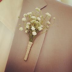 a boutonniere with white flowers is attached to the lapel of a suit