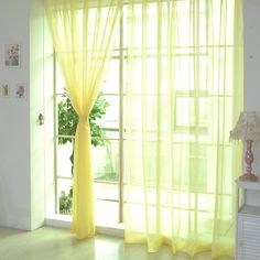 yellow curtains are hanging in front of a window