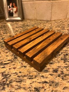 a wooden slat sitting on top of a counter next to a framed photo in a frame