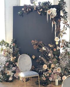 a chair sitting on top of a wooden floor next to a wall covered in flowers