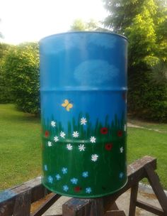 a large blue barrel sitting on top of a wooden bench next to a green field