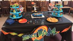 a table topped with cakes and cupcakes on top of a black table cloth