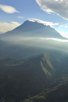 an aerial view of a mountain range with clouds in the sky and sun shining on it